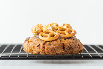 Fresh chocolate American chip cookie decorated with salted camel and caramel popcorn on cooling rack. Close up on white background