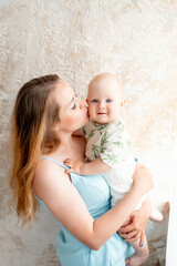 a mother with a small child, a mother with a newborn baby at home, smiling, hugging, and kissing, a happy family at home, a mother's tenderness, love, and care