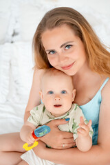 mom with a small child, mom with a newborn baby at home on the bed smiling, hugging and kissing, a happy family at home, mom's tenderness, love and care