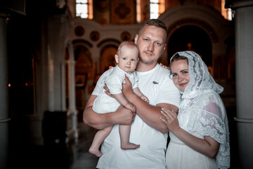Christian family with a small child in the church, father, mother, and baby in the church, the...