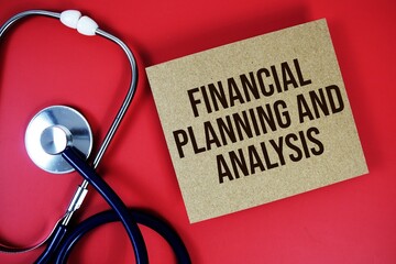 Financial Planning and Analysis text written on paper card with stethoscope on red background