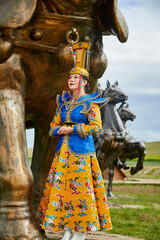 Fototapeta premium Mongolian girls dressed in luxurious Mongolian costumes on the Mongolian war chariots of the Jinyuan Grand Tent on the grassland