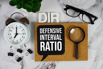 DIR - Defensive Interval Ratio acronym with alarm clock and magnifying glass, business concept...