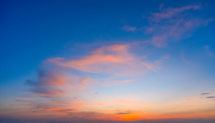 Radiant pink, orange, and blue clouds are scattered across the sky during the evening. The sun is setting in the distance, casting warm light across the celestial landscape