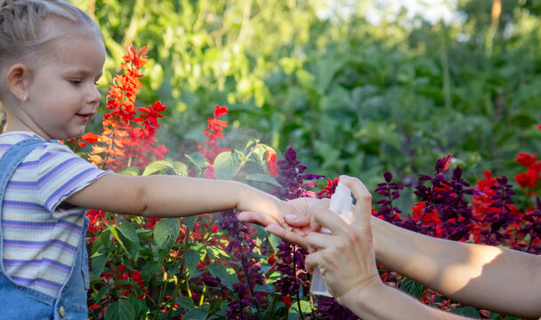 A mother sprays her child with mosquito repellent.