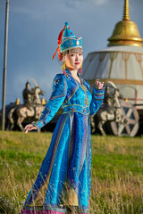 Obraz premium Mongolian girls dressed in luxurious Mongolian costumes in front of a yurt on the grassland