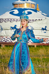 Obraz premium Mongolian girls dressed in luxurious Mongolian costumes in front of a yurt on the grassland