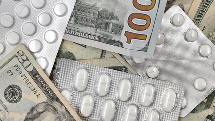 Background view of a white medical tablets over a 20 and 100 US dollar bills, symbolizing the high...