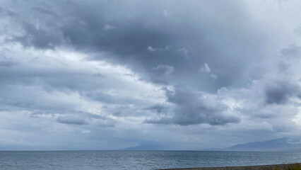 Stormy Clouds Over a Calm Sea with Distant Mountains