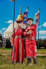 Obraz premium A young couple in traditional Mongolian clothing in front of a yurt on the grassland