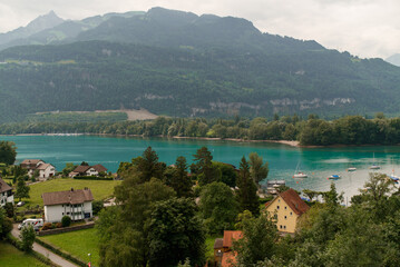 Fototapeta premium View of Lake Walen, Switzerland, Swiss Alps, Canton St. Gallen, Chatzenberg, summer 2025. Trees, meadows and small villages in the valley. mountains, beautiful landscape hiking, recreation.