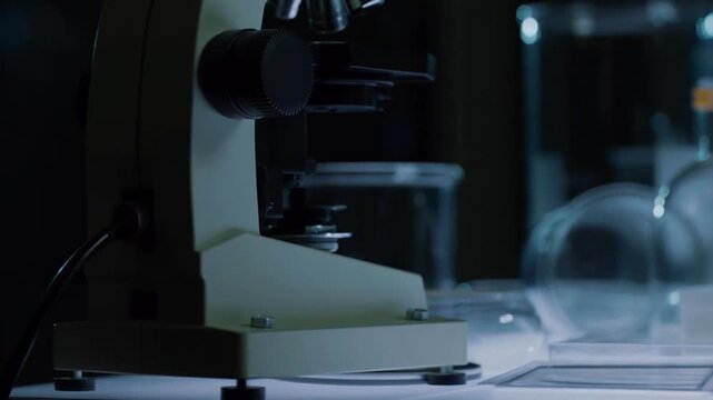 Pan across microscopes and petri dishes under soft laboratory light