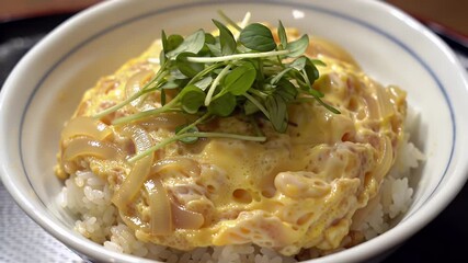 Close Up of Golden Oyakodon Rice Bowl Topped with Fresh Greens Featuring Simmered Chicken Onions and Fluffy Egg in Savory Dashi Broth Perfect for Japanese Cuisine and Culinary Presentation