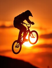 Obraz premium Silhouette of BMX cyclist jumping against sunrise