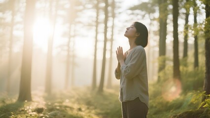 A person meditating with hands clasped in a serene forest bathed in soft sunlight.