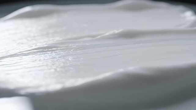 High-end macro of rich cream spread on glass with light traveling across the surface, showcasing depth and moisture