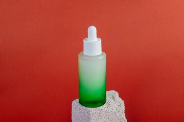 Green glass cosmetic bottle, Skin care or sunscreen cosmetic with stylish props on cream background.
