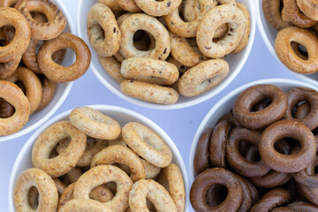 Freshly baked mini bagels on a dark background. Top view. Pretzels in the form of a ring close-up. Small bread circle biscuit. Bowls with different types of bagels.
