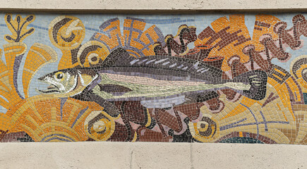 architectural relief features two cherubic figures holding grape clusters, seated symmetrically above a decorative window frame of historic buildings in Lille, France.