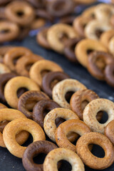 Freshly baked mini bagels on a dark background. Top view. Pretzels in the form of a ring close-up. Small bread circle biscuit. Bowls with different types of bagels.
