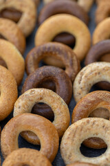 Freshly baked mini bagels on a dark background. Top view. Pretzels in the form of a ring close-up. Small bread circle biscuit. Bowls with different types of bagels.
