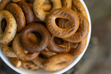 Freshly baked mini bagels on a dark background. Top view. Pretzels in the form of a ring close-up. Small bread circle biscuit. Bowls with different types of bagels.
