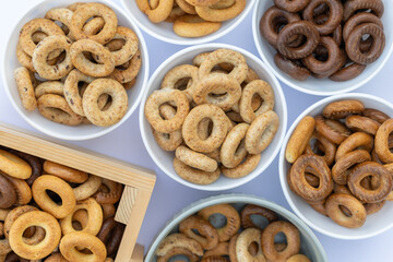 Freshly baked mini bagels on a dark background. Top view. Pretzels in the form of a ring close-up. Small bread circle biscuit. Bowls with different types of bagels.
