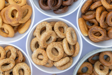 Freshly baked mini bagels on a dark background. Top view. Pretzels in the form of a ring close-up. Small bread circle biscuit. Bowls with different types of bagels.
