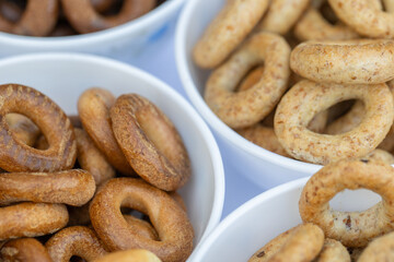 Freshly baked mini bagels on a dark background. Top view. Pretzels in the form of a ring close-up. Small bread circle biscuit. Bowls with different types of bagels.
