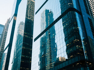 Reflection of tall skyscrapers on the glass facade of a modern high-rise office building in the city. Ideal for business, finance, corporate branding, real estate promotion, and urban architecture