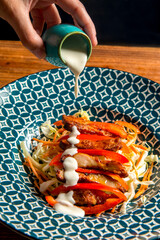 Close-up of chicken salad with red cherry tomatoes, fresh vegetables, red peppers and yogurt