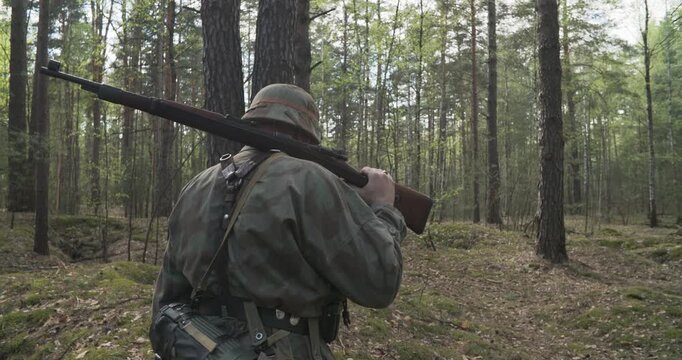 Reenactor Dressed As German Infantry Soldier Going By Forest In Slo-mo Slow Motion Slow-mo. Soldier With Carabines Mauser 98k Combing Forest Autumn Season. Wermacht Uniform. Reenactment Tactic Game