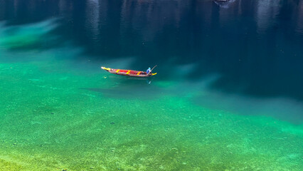 Scenic view of a wooden boat floating on the crystal-clear Dawki River in Meghalaya, India.

