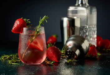 Cocktail with ice, strawberries, and rosemary.