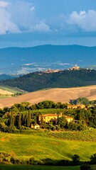 Fototapeta premium Rolling hills, farmland, and a distant village bathed in the golden light of sunset