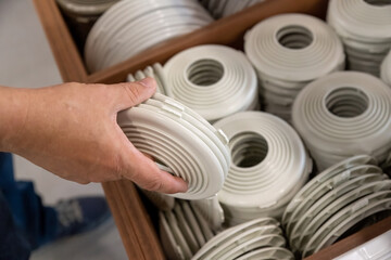 Customer selecting white plastic trim rings for stretch ceiling installation in a hardware store, used to secure and finish recessed lighting openings.