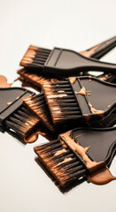 Close up of several hair dye brushes with copper color dye on bristles