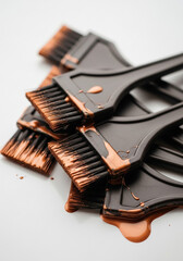 Pile of hair dye brushes with copper tones and dripping color