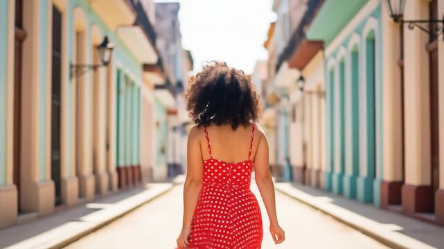 Happy woman in a red polka dot dress dancing on a colorful street in havana on vacation
