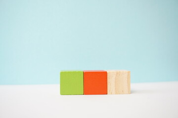 Three wooden cubes colored green, orange, and natural wood arranged in a line, perfect for conceptual and educational uses like teaching, planning, and creative projects.