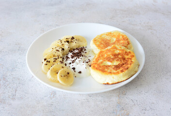 Homemade Pancakes with Banana Slices and Cream on a White Plate