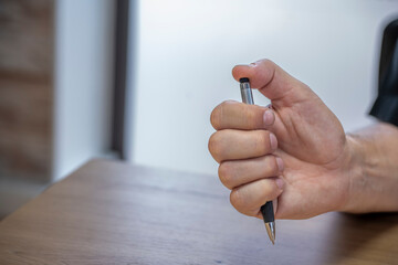 Main d'un homme jouant avec son stylo au travail © Esta Webster