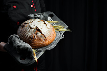 Female hands hold Fresh Bread on black background. Top view.