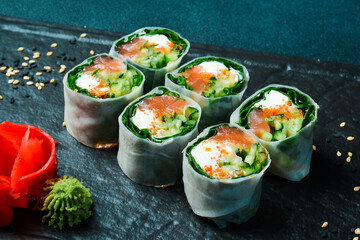 sushi rolls with salmon, kale leaves, and cream cheese. Served with wasabi sauce and pickled ginger. Japanese traditional food. Close up.