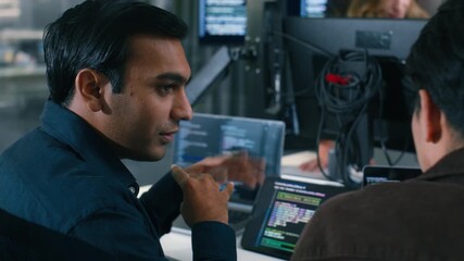 Two Software Developer, Programmer discussing, explaining to colleague working on code, application software development project using desktop computer, work together in co-working office space. - Powered by Adobe