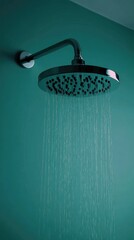 Chrome shower head spraying water on teal wall (2)