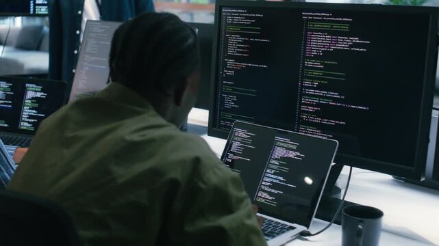 Professional African American male Software Engineer Pointing to desktop computer screen monitor checking line code, examining, planning to development application in Co working Office Space.