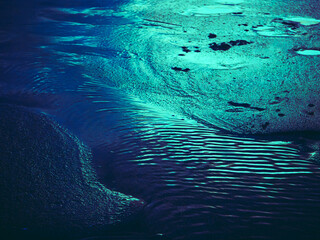Artistic turquoise reflections on wet sand in Aviles, Asturias, Spain