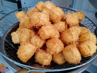 Tahu Crispy or Crispy golden fried tofu cubes drained on a wire strainer, showing crunchy texture and savory street food snack from Indonesia