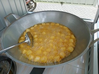 Tahu crispy or Golden crispy tofu cubes are being deep-fried in a large pan filled with hot oil, showing a delicious street food snack with crunchy texture and appetizing golden color.